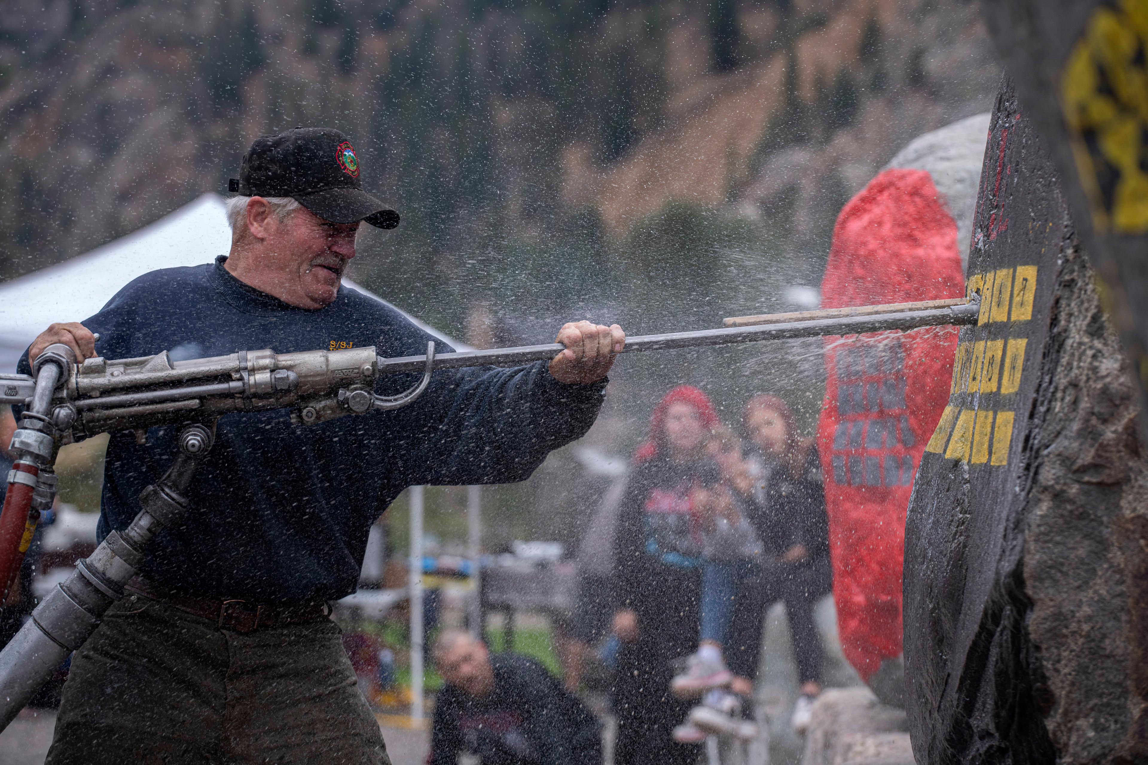 Man using a hard rock power drill tries to break up a rock in a mining games competition.