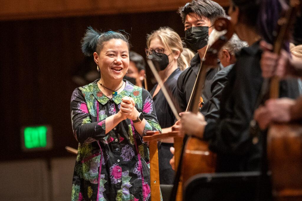 An orchestra at a performance during the Colorado Music Festival. On the front of the stage is composer Wang Jie.