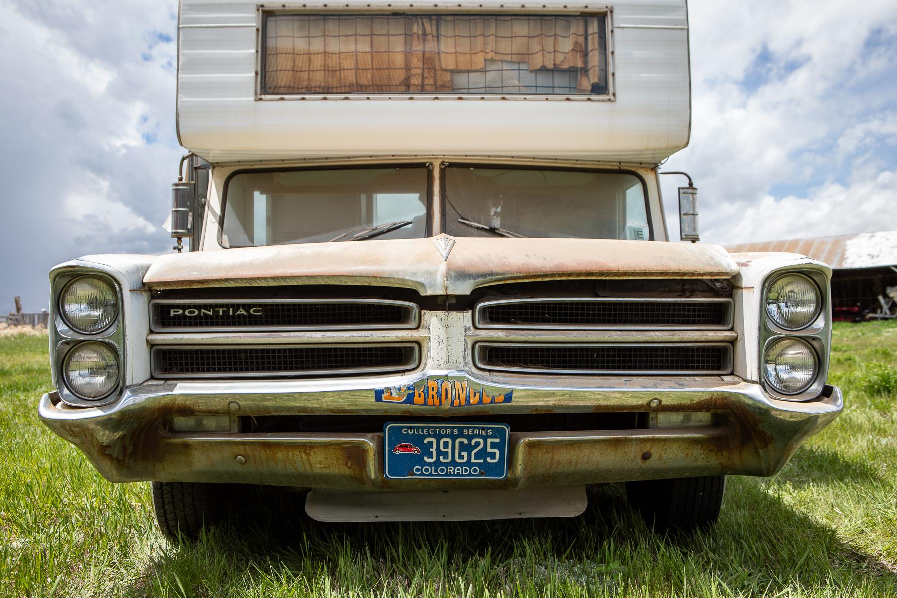 The front grille of a 1966 Pontiac Catalina with a peeling Broncos sticker on the front bumper.