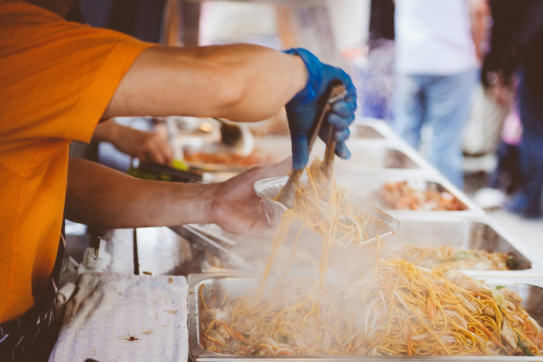 Steaming hot noodles being placed in a to go container