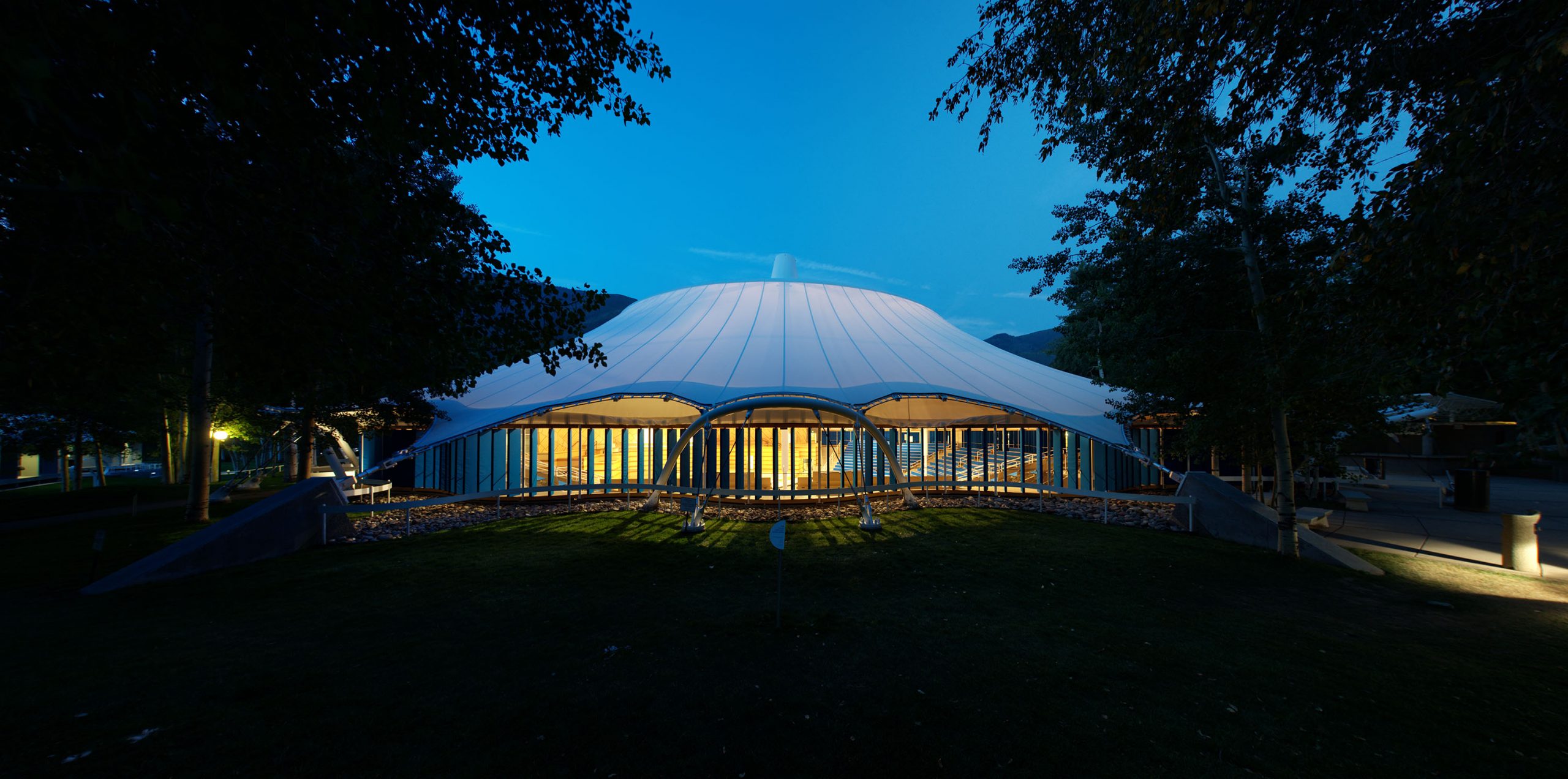 The camera looks at an illuminated Klein Music Tent in Aspen at dusk.