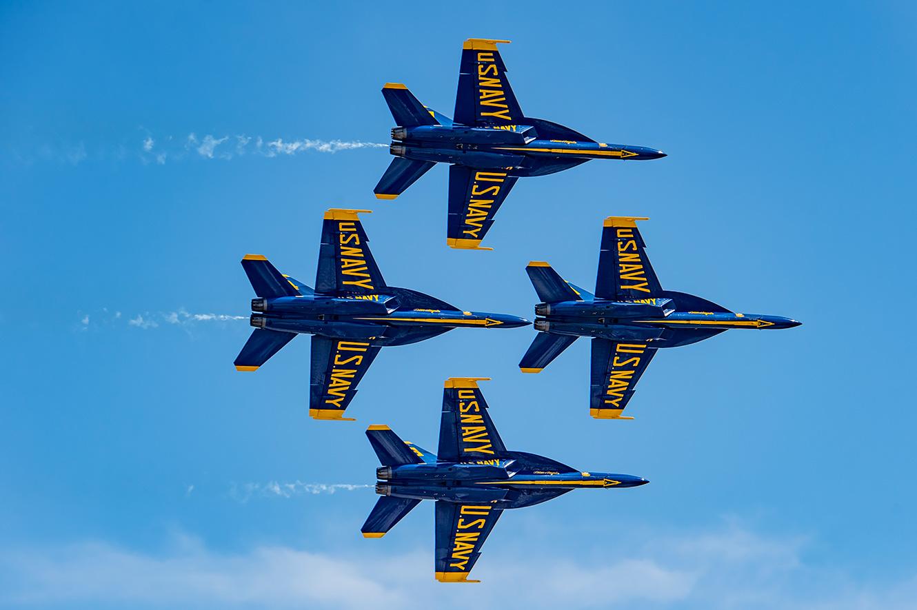 Yellow and blue jets labled with U.S. Navy fly in formation.