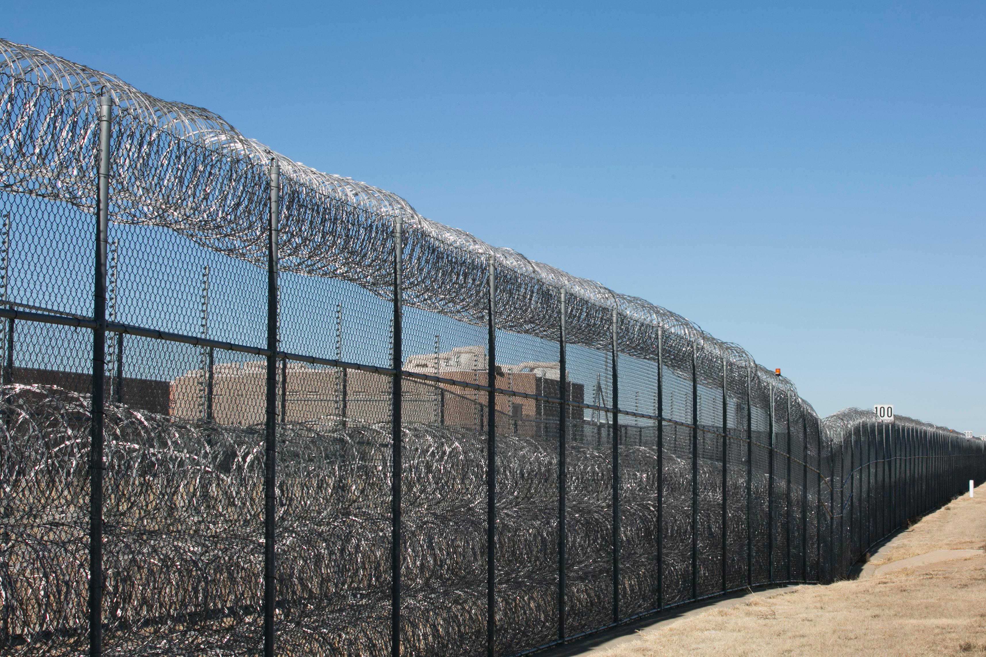 Barbed wire fence leading to a correctional facility