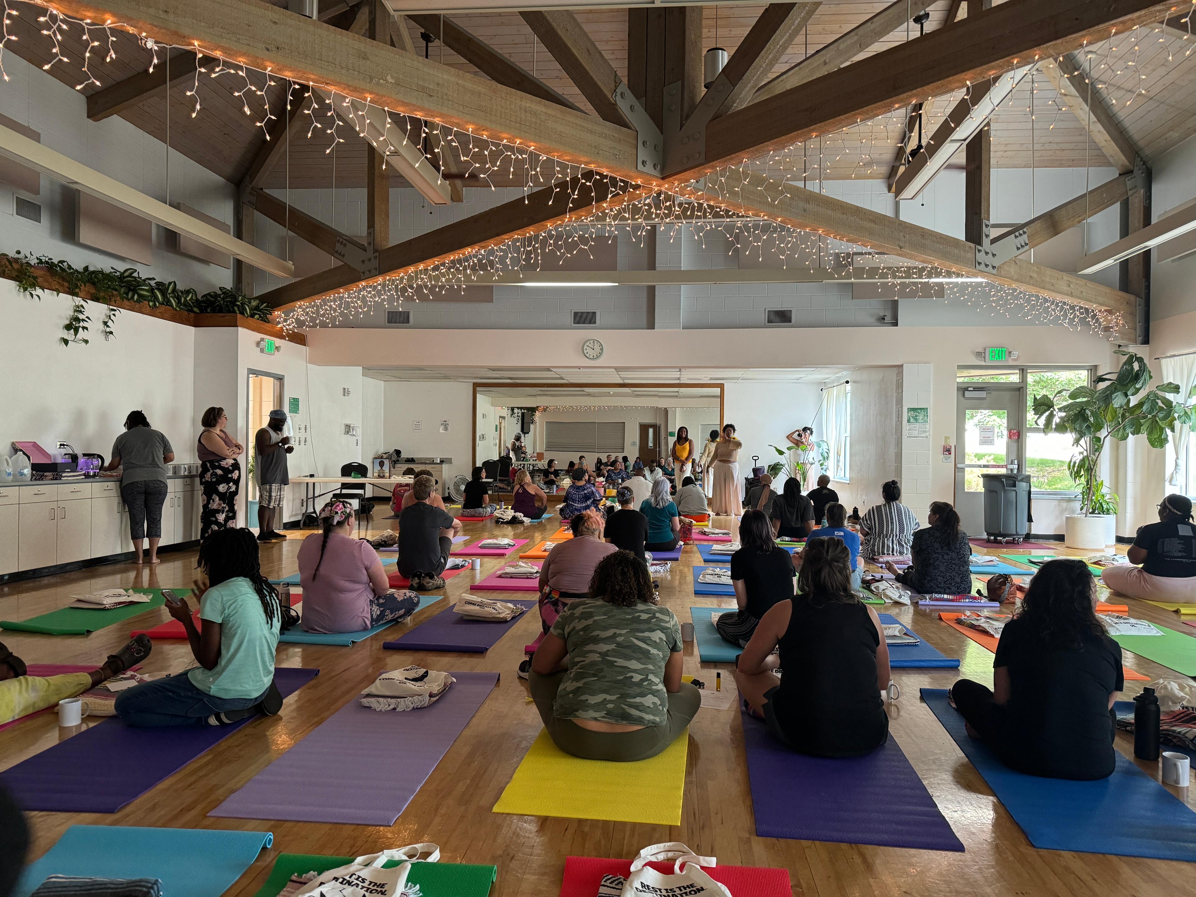 A group of people sit on yoga mats awaiting the start of Rest as Resistance: A Community Nap