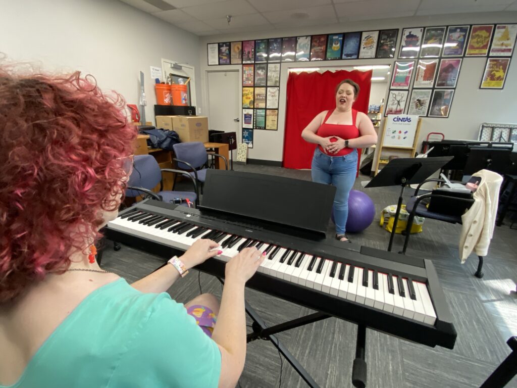 Voice instructor Corrine Mellon plays a keyboard as opera singer Chloe Scull tries to sing.